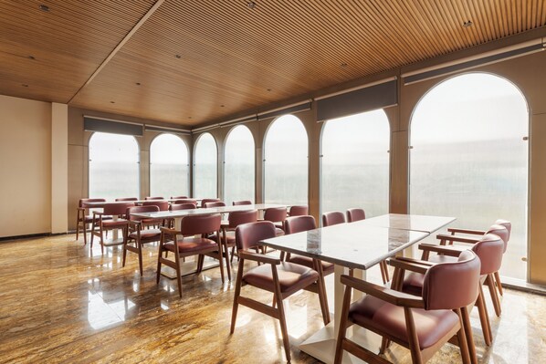 Un salón de conferencias con una gran mesa y sillas, amplias ventanas de arco y techo de madera.