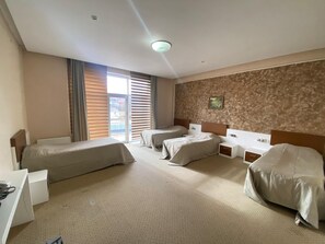 Ein Hotelzimmer mit zwei Betten, einem Schreibtisch und einem Fenster mit Jalousien.