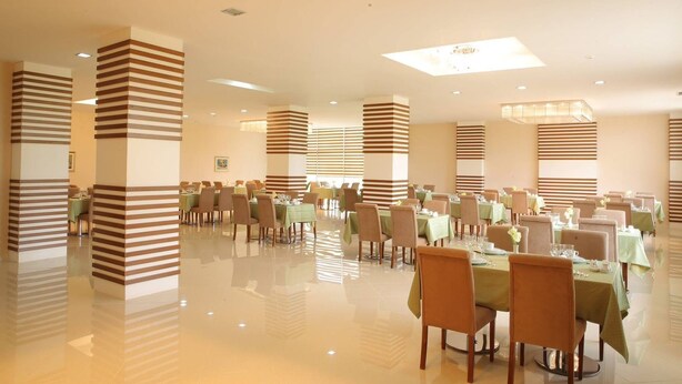 A spacious dining area with multiple tables and chairs, featuring striped columns and a polished floor.
