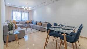 Un salon moderne avec une table à manger en verre, des chaises bleues, un canapé et une table basse.