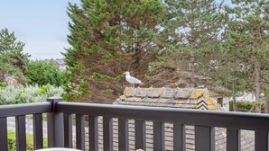 A balcony with a table set for two, a bowl of fruit, and a seagull statue. - Les Terrasses de Tourgeville by Interhome (Deauville-Trouville)