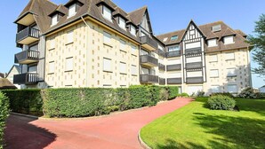 A multi-story residential building with a symmetrical facade, multiple balconies, and a red pathway leading to the entrance. - Les Terrasses de Tourgeville by Interhome (Deauville-Trouville)