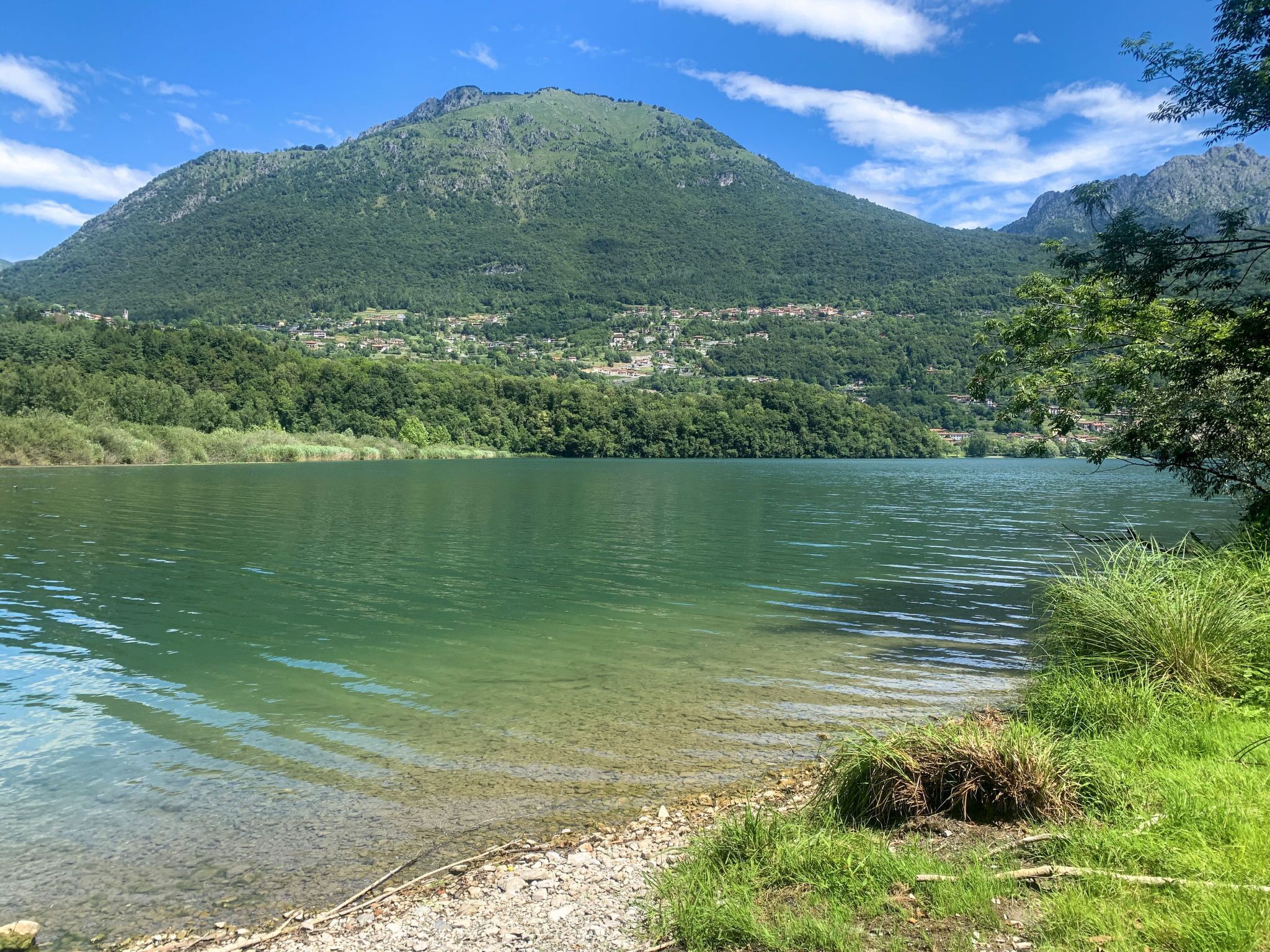 A clear view of a lake with a mountain in the background and a small settlement on the opposite shore.