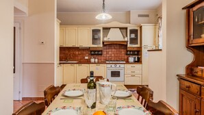 A dining room with a table set for four, featuring a bowl of fruit, wine, and glasses.