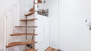 A white interior with a spiral staircase, a white door, and a small shelf with a picture. - Charme et Confort by Interhome (Vannes)