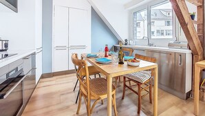 A modern kitchen with a dining area, featuring a wooden dining table, chairs, and a hanging light fixture. - Charme et Confort by Interhome (Vannes)