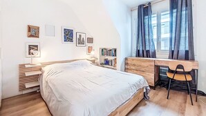 A bedroom with a bed, a desk, and a chair. There are bookshelves with books and framed pictures on the wall. - Charme et Confort by Interhome (Vannes)