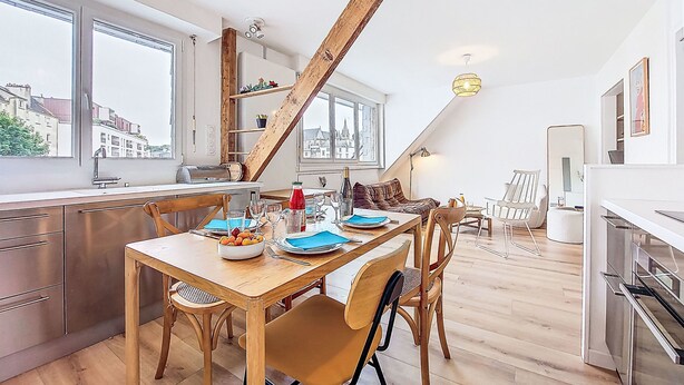 A modern kitchen with a dining area, wooden beams, large windows, and a city view. - Charme et Confort by Interhome (Vannes)