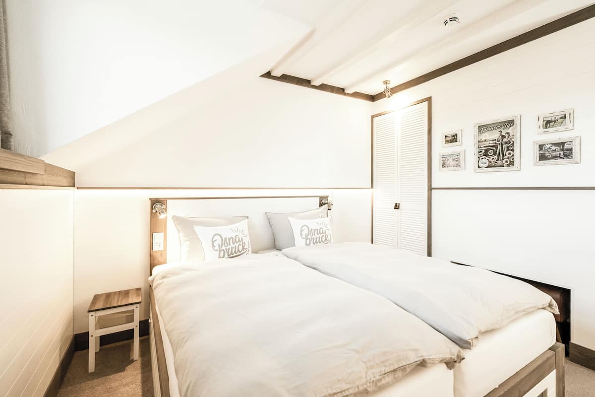 A bedroom with a bed, bedside table, and a wall with framed pictures.