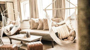 Un salon chaleureux avec un canapé, deux hamacs, une table basse et des poufs en cuir.