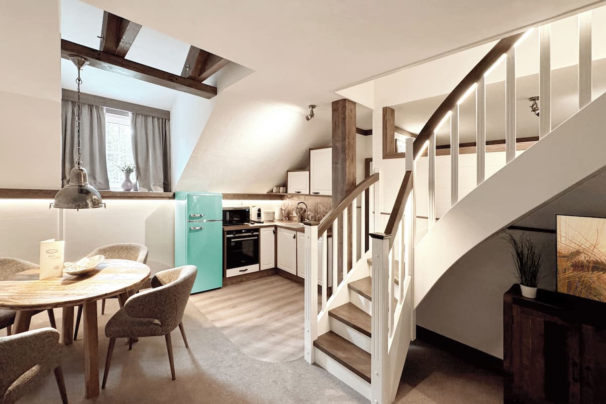 A modern kitchen with a dining area, a staircase, and a view of the outdoors.
