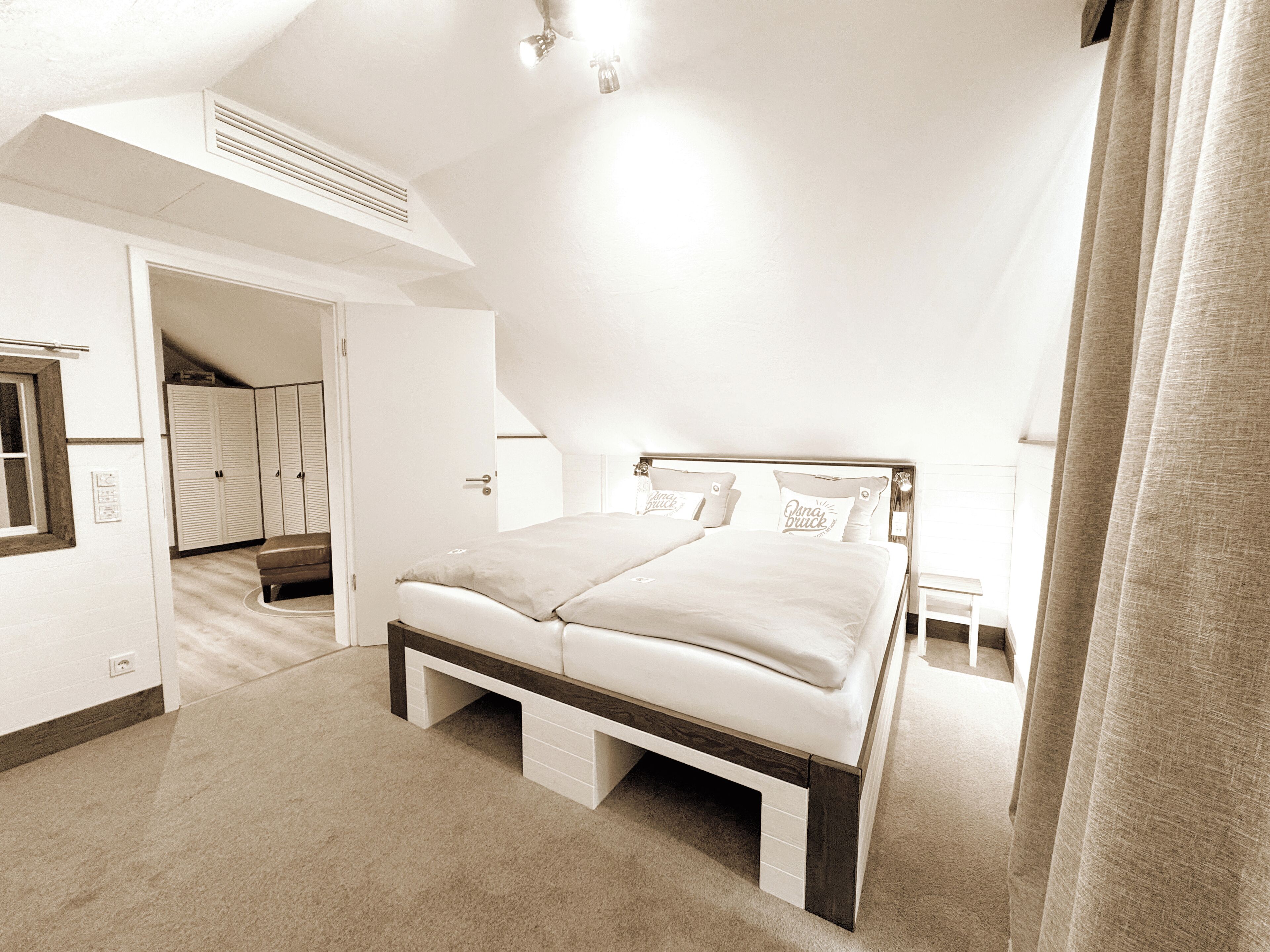 Un dormitorio con cama, armario y puerta que da a otra habitación.