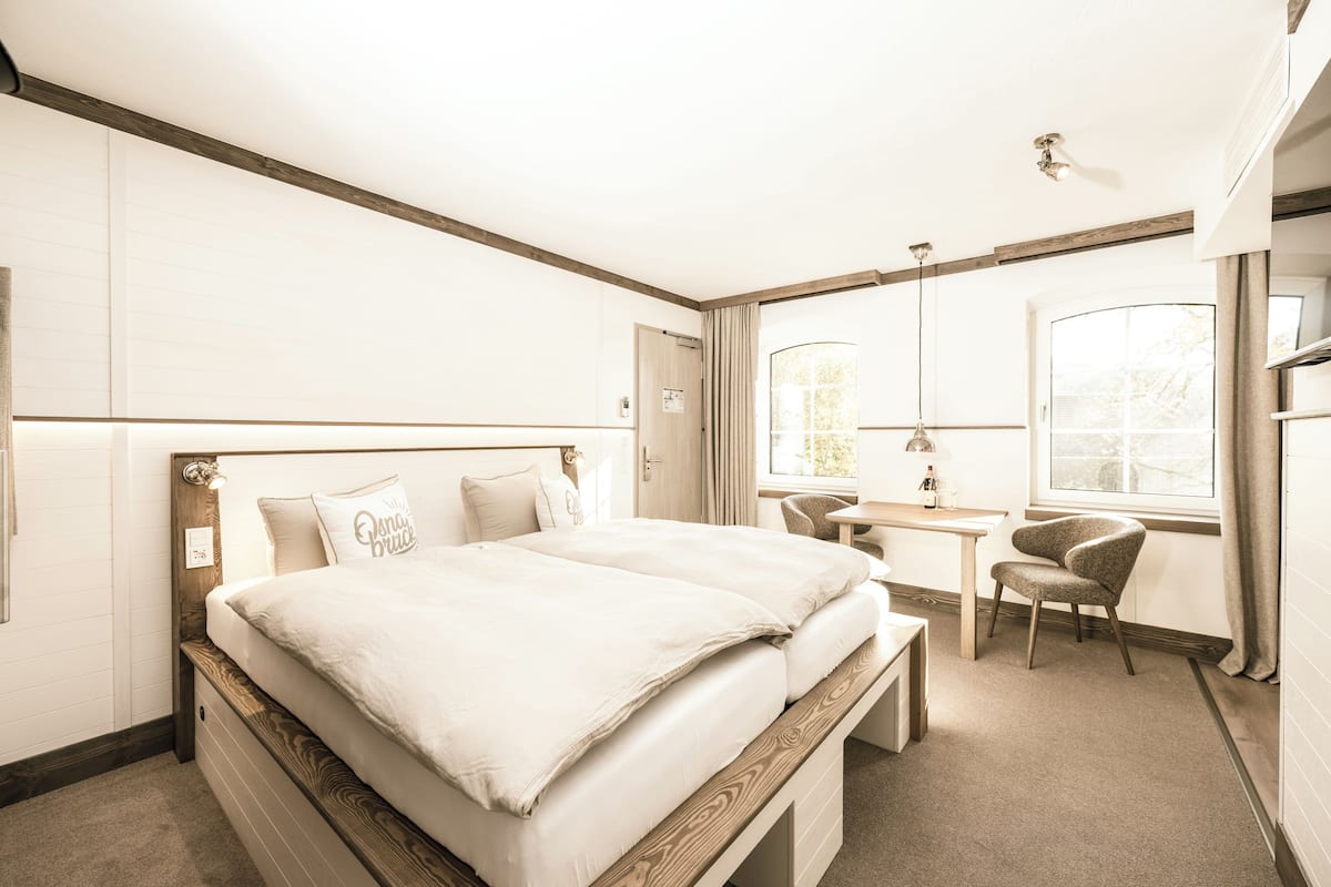 A bedroom with a bed, bedside table, chair, and a window with curtains.