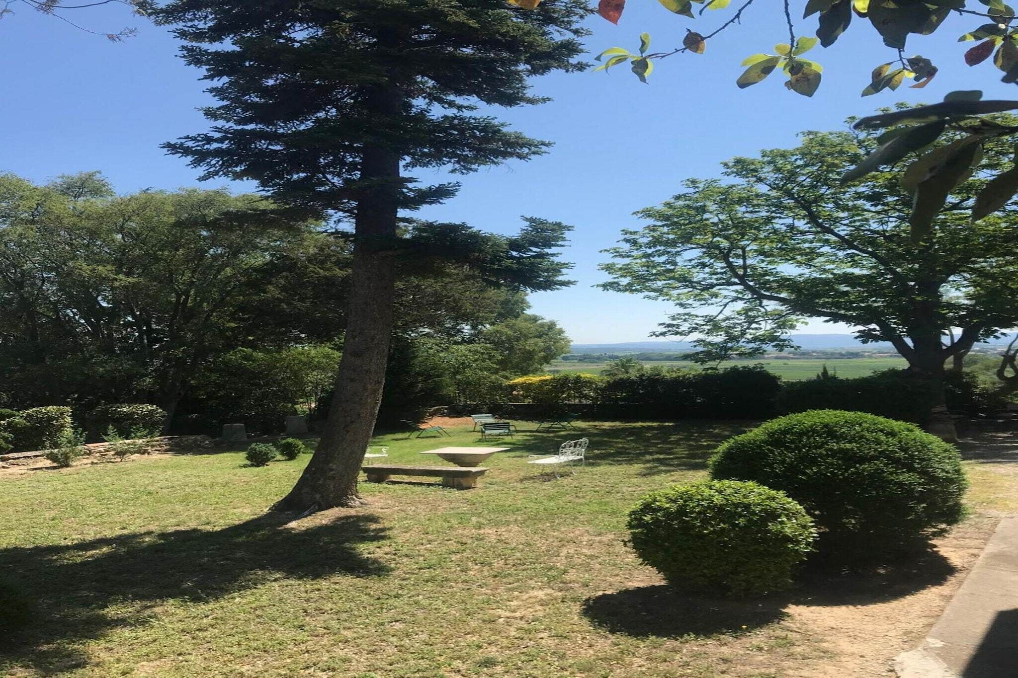 A garden with a picnic table, benches, and a view of the countryside.