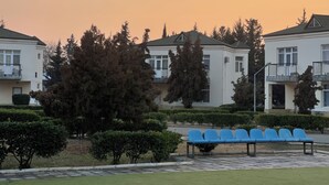 A row of blue chairs in a courtyard with a row of white buildings in the background. - Arena Hotel Kurdamir (Kurdamir)