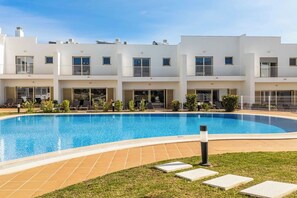 Un edificio moderno con piscina, diversi balconi e aree salotto all'aperto.