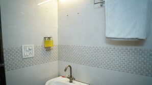 A bathroom with a sink, a mirror, a towel hanging on the wall, and a soap dispenser. - Hotel Blue Sky By Admire Stays (New Delhi)
