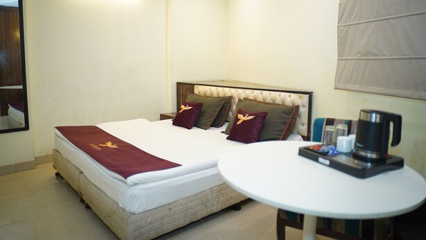 A hotel room with a bed, a round table with a coffee maker, and a mirror on the wall. - Hotel Blue Sky By Admire Stays (New Delhi)