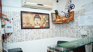 A reception area with a Buddha statue, a cash counter, and patterned wallpaper. - Hotel Blue Sky By Admire Stays (New Delhi)