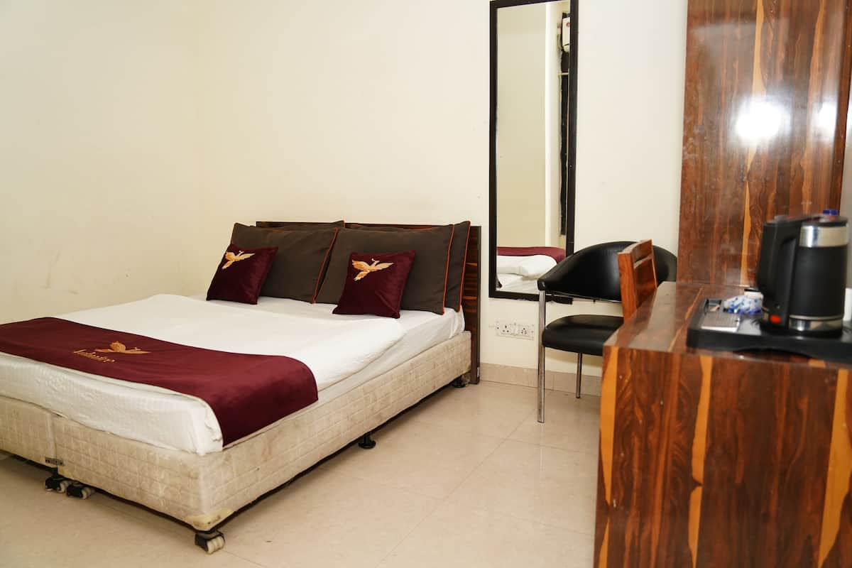 Een hotelkamer met een bed, een houten bureau en een spiegel.