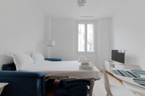 Une chambre d’hôtel avec un lit, une télévision, un bureau et une fenêtre.