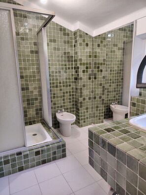 A bathroom with green mosaic tiles, a shower enclosure, a bidet, and a bathtub. - Waterfront 3-room apartment (Saint-Raphaël)