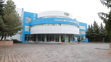 Un bâtiment moderne à la façade bleue et blanche, orné du logo des anneaux olympiques.