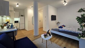 A modern, well-lit living area with a sofa, a small table, and a TV mounted on the wall.