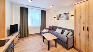 A modern living room with a sofa, a coffee table, a TV, and a radiator. - Hotel Erlebnis Wald (Johanngeorgenstadt)