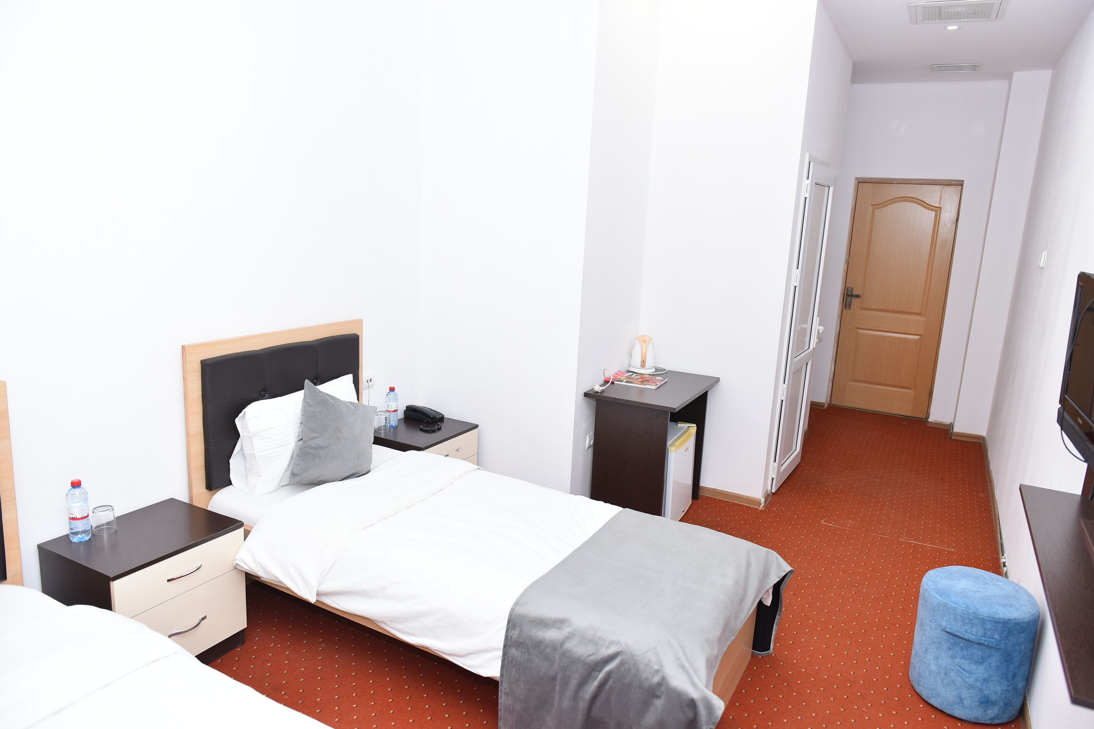A hotel room with a bed, bedside tables, a desk, a chair, and a television.