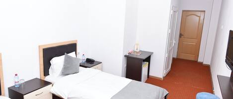 A hotel room with a bed, bedside tables, a desk, a chair, and a television.