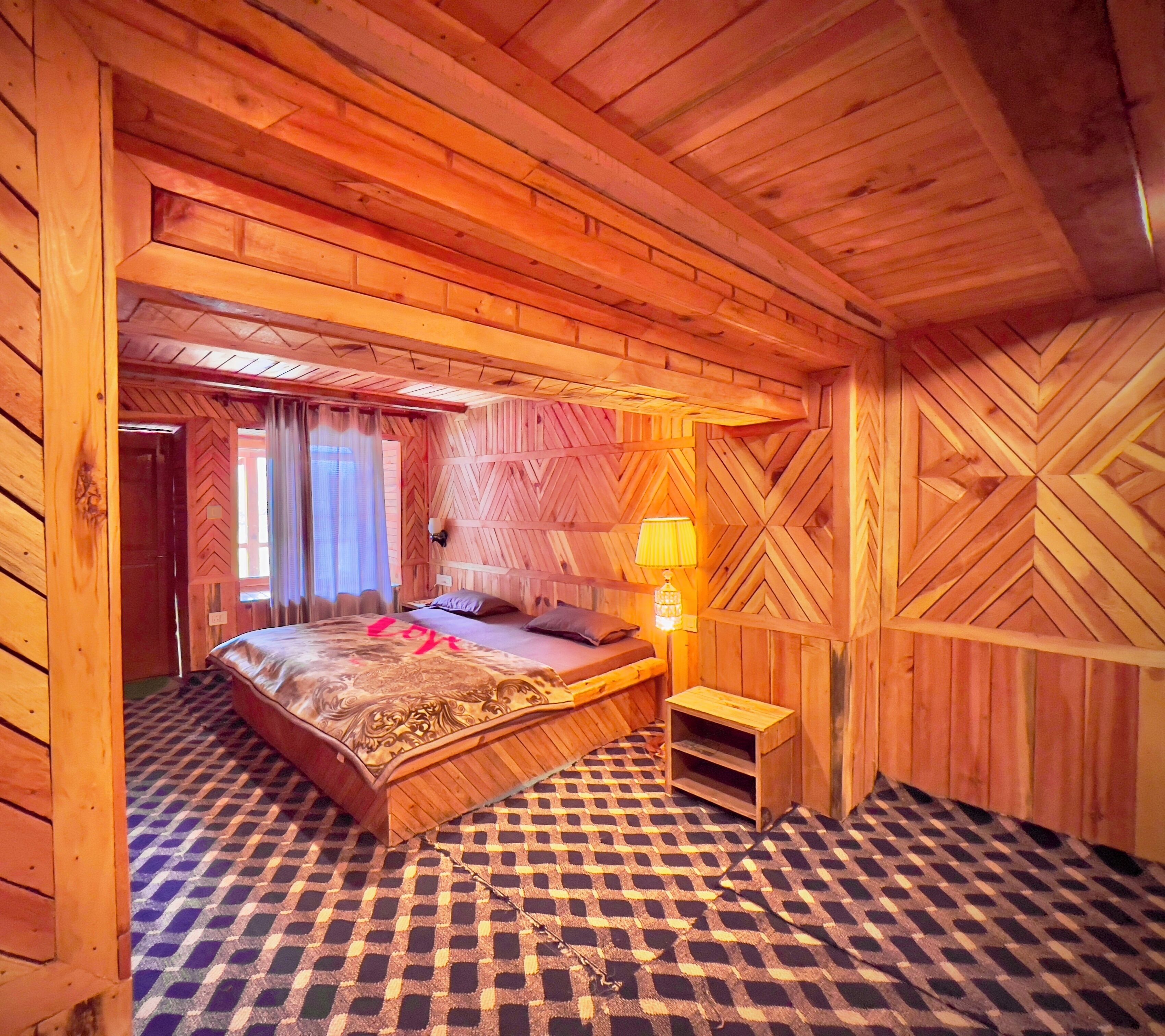 A wooden room with a bed, a nightstand, and a lamp.