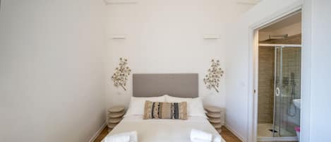 Un dormitorio moderno con una cama grande, cabina de ducha de vidrio y vestidor.