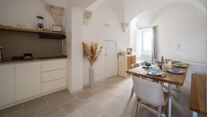 A kitchen with white cabinets, a wooden countertop, and a dining table set for two. - Il Palazzotto: elegant historic residence in the heart of Ostuni with panoramic (Ostuni)