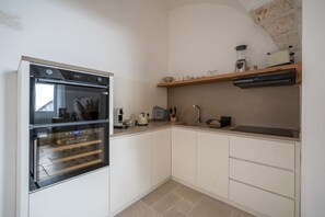A kitchen with a built-in oven, a countertop with a blender, a toaster, and a shelf with kitchen items. - Il Palazzotto: Historic Residence with Sea View in Ostuni (Ostuni)