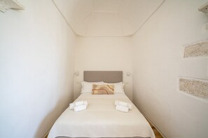 A small, neatly made bed with a headboard, two pillows, and two rolled towels. - Il Palazzotto: Historic Residence with Sea View in Ostuni (Ostuni)