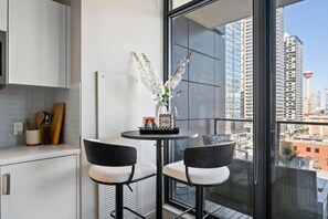 Une cuisine moderne avec des meubles blancs, une table ronde accompagnée de deux chaises et un vase rempli de fleurs blanches.