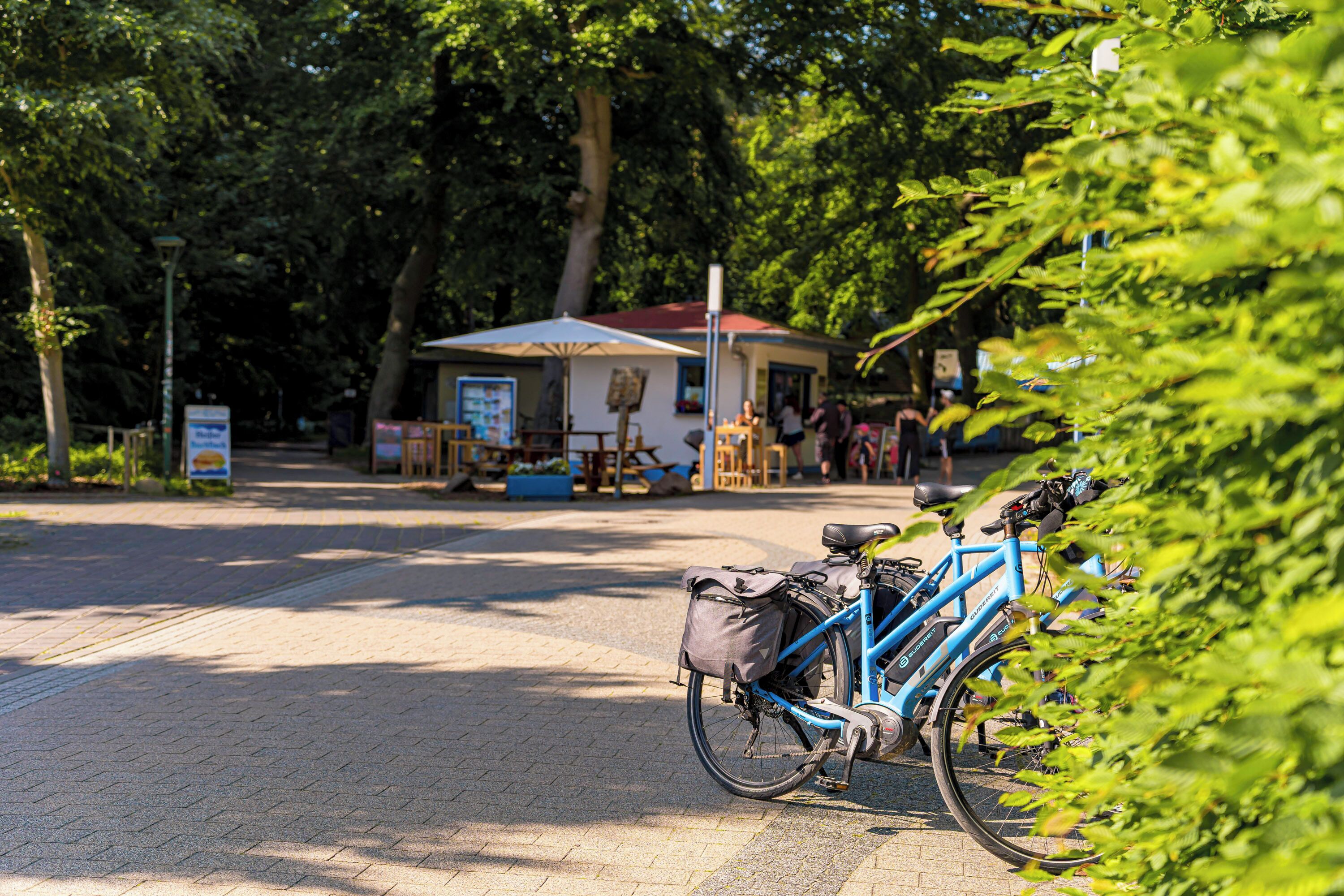 Uma bicicleta estacionada em área pavimentada, com um pequeno edifício ao fundo.