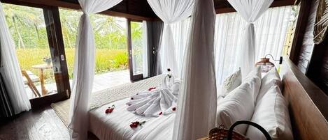 Un dormitorio con cama a dosel, una cesta de mimbre y vistas al exterior.