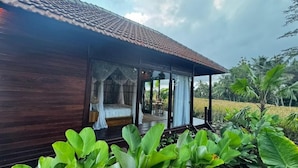 A wooden building with a thatched roof, large windows, and a covered porch. - Eco Oasis Wooden Villa (Tegallalang)