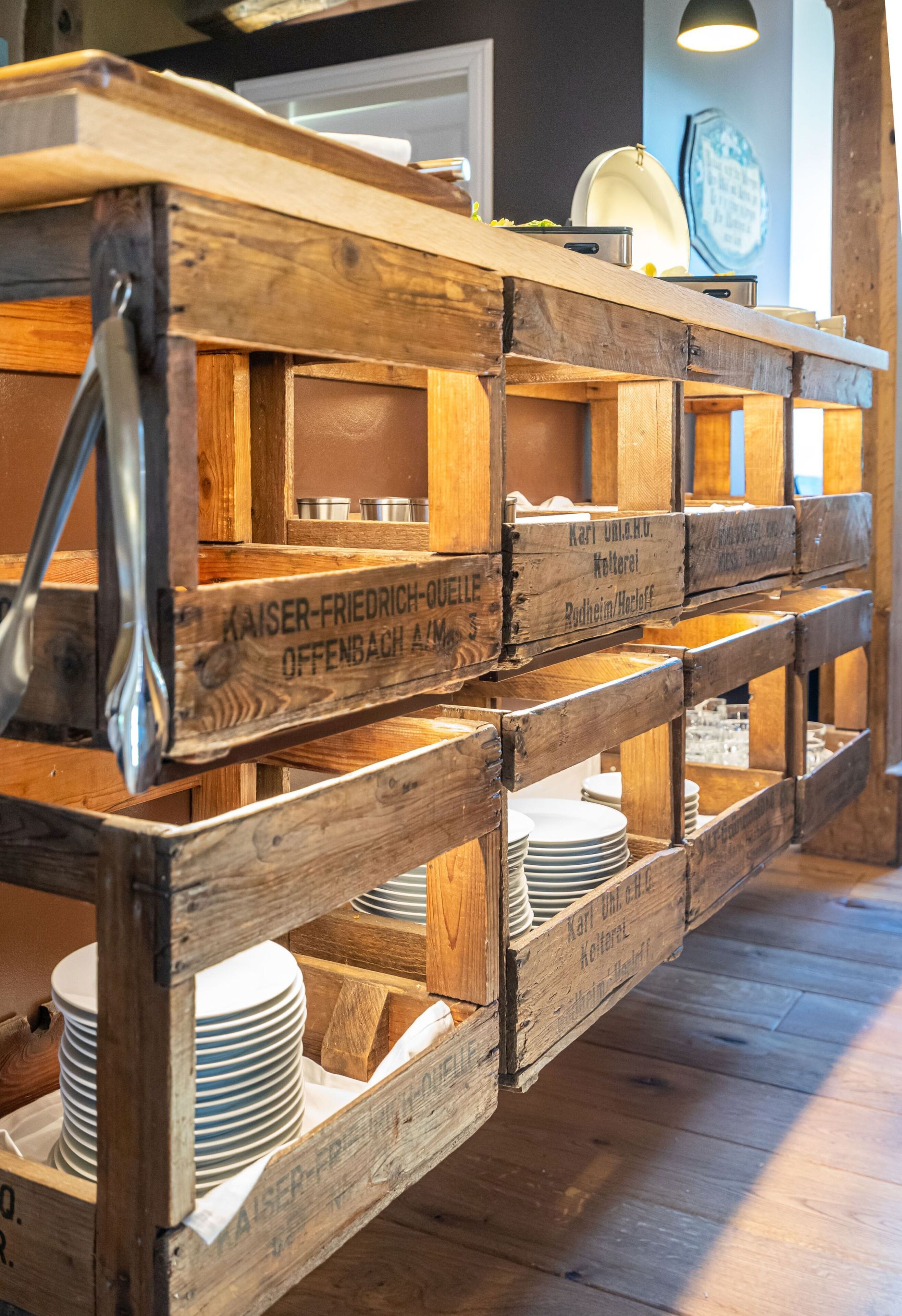 Un présentoir en bois, doté de compartiments étiquetés et contenant des piles d’assiettes.