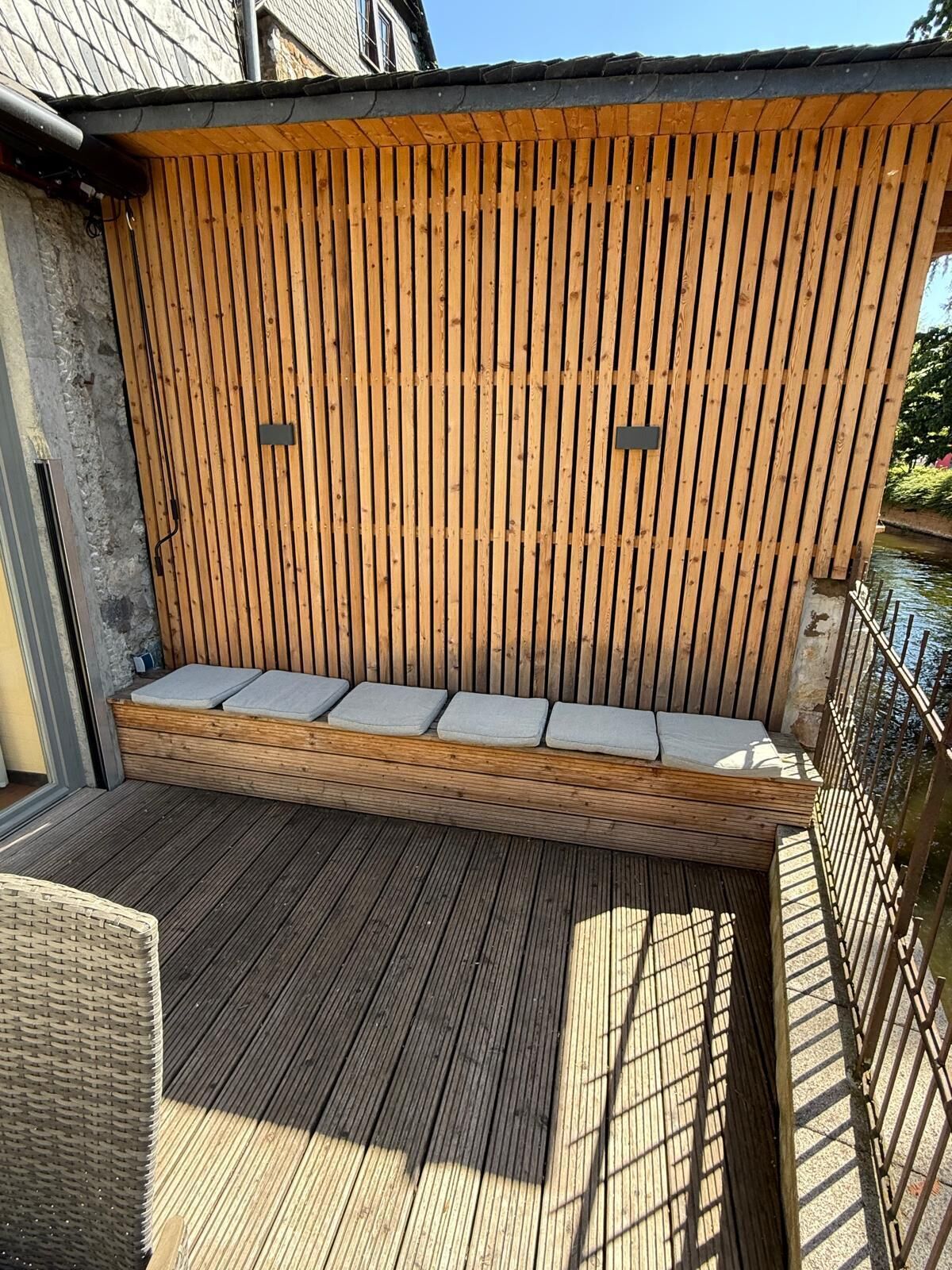 A wooden deck with a built-in bench and cushions.