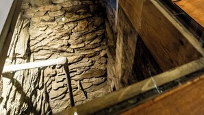 A room with a glass-bottomed aquarium, wooden flooring, a stone wall, and a wooden column. - Boutique-Hotel Stadtherberge Wetzlar (Wetzlar)