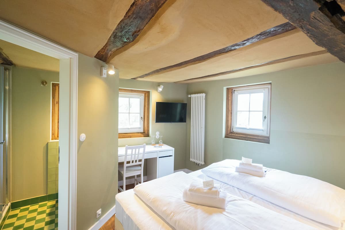 Une chambre d’hôtel avec un lit, un bureau, une chaise, une télévision et une fenêtre.