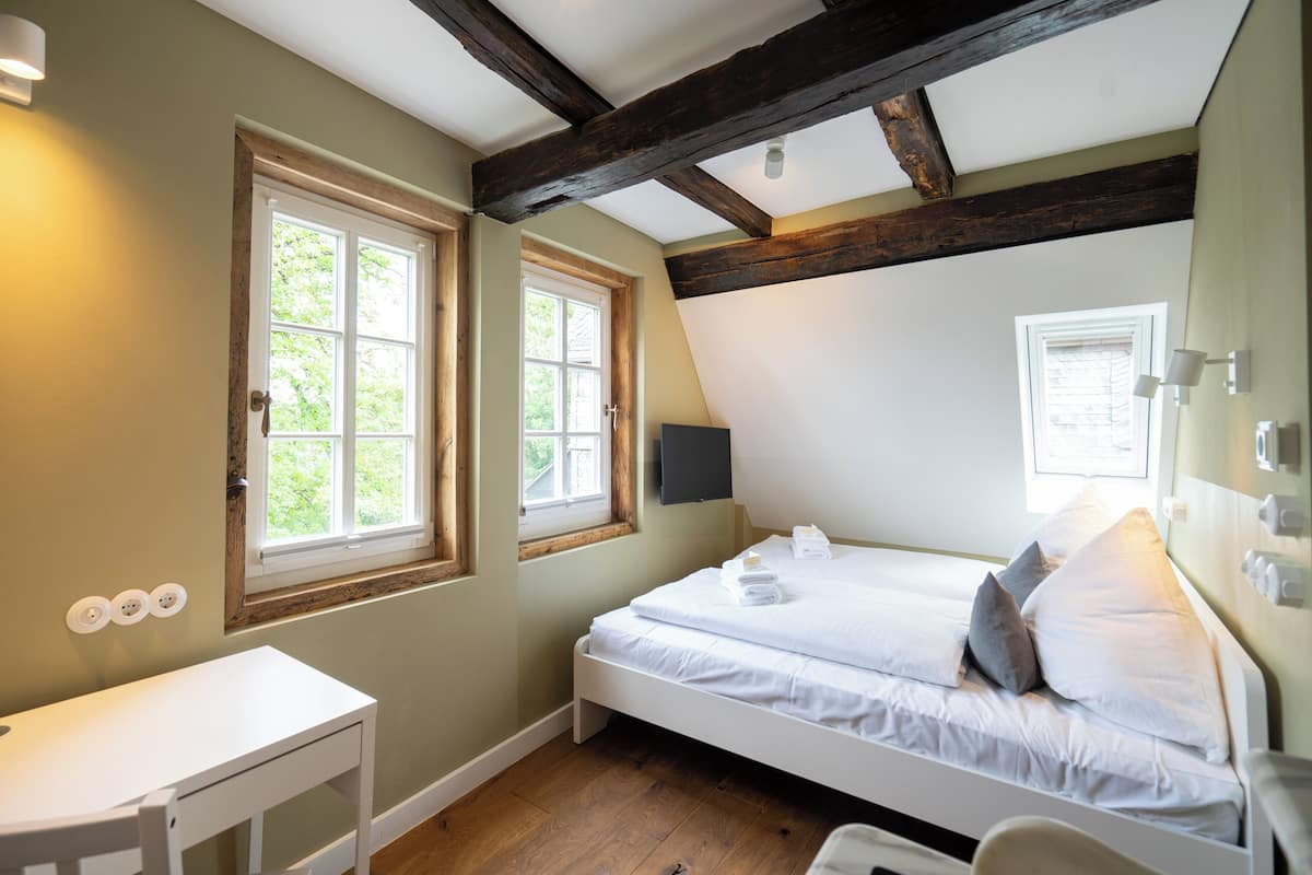 Une chambre à coucher avec un lit, un bureau et deux fenêtres.