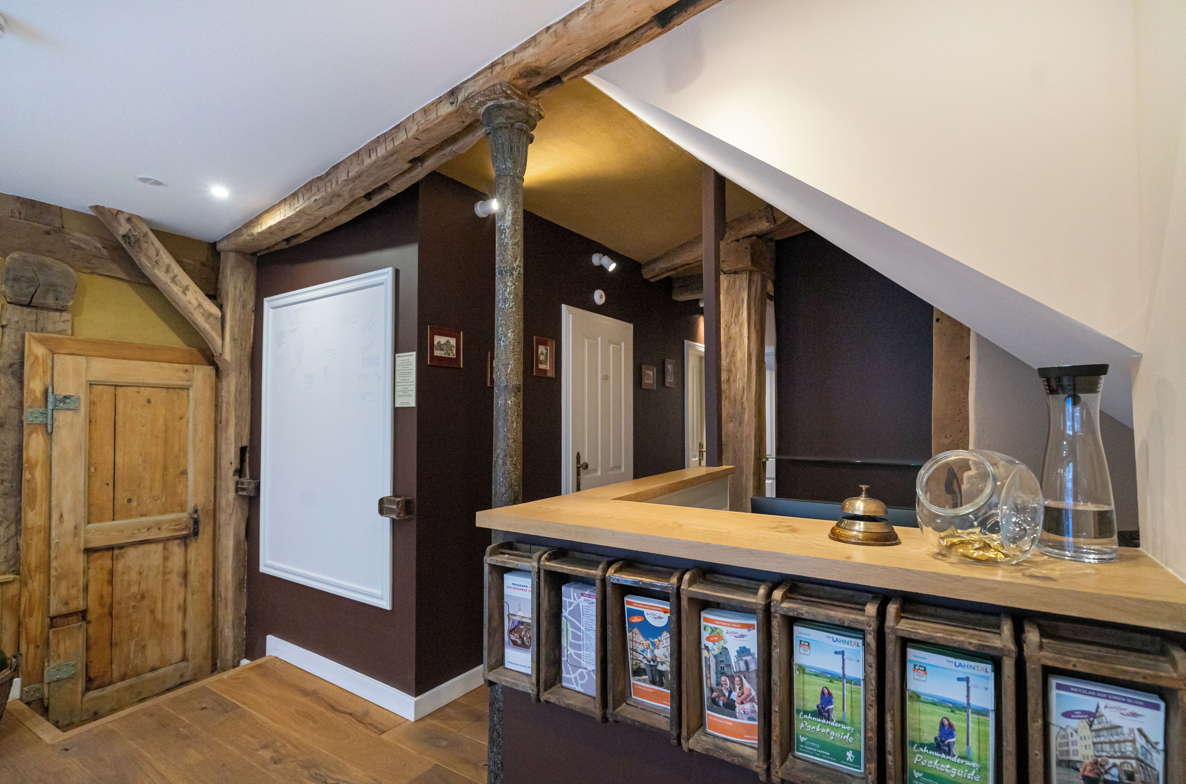 A wooden interior with a reception desk, framed informational posters, and a door.