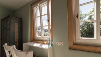 A room with a window, a white chair, a small table, and a cabinet.