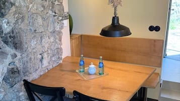 Una mesa de comedor de madera con dos sillas, una lámpara colgante y una pared de piedra.