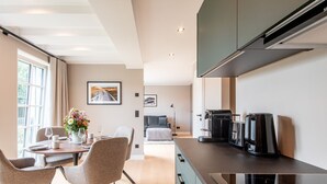 A modern kitchen with a built-in stove, a coffee machine, and a dining area with a table and chairs. - F'27 Living, Whg. 06 - F27 Living (Sylt)