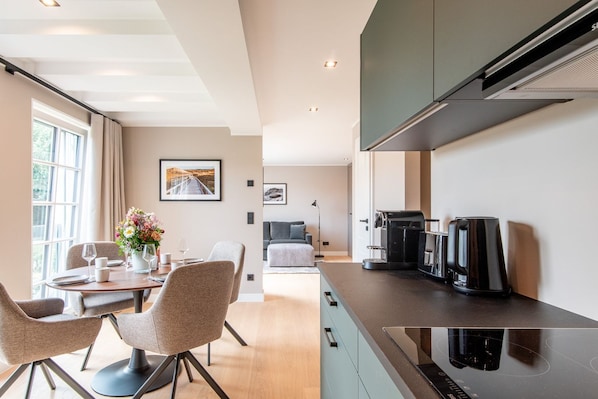 Una cocina moderna con estufa integrada, cafetera y comedor con mesa y sillas.